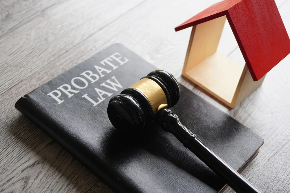 Gavel and a book titled "Probate Law" alongside a small wooden house model, symbolizing estate planning and property transfer in Texas.