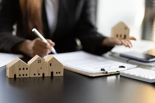 Woman writing on clipboard with miniature wooden houses, symbolizing estate planning and probate law in Texas.