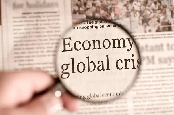 Magnifying glass focusing on the words "Economy" and "global crisis" in a newspaper, highlighting economic challenges relevant to probate and estate planning in Texas.