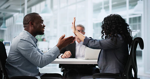 African American mediator facilitating a tense discussion between two individuals in a modern office setting, highlighting conflict resolution in family disputes related to probate issues.