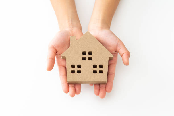 Hands holding a small cardboard house model, symbolizing inherited property and the complexities of estate law in Texas.