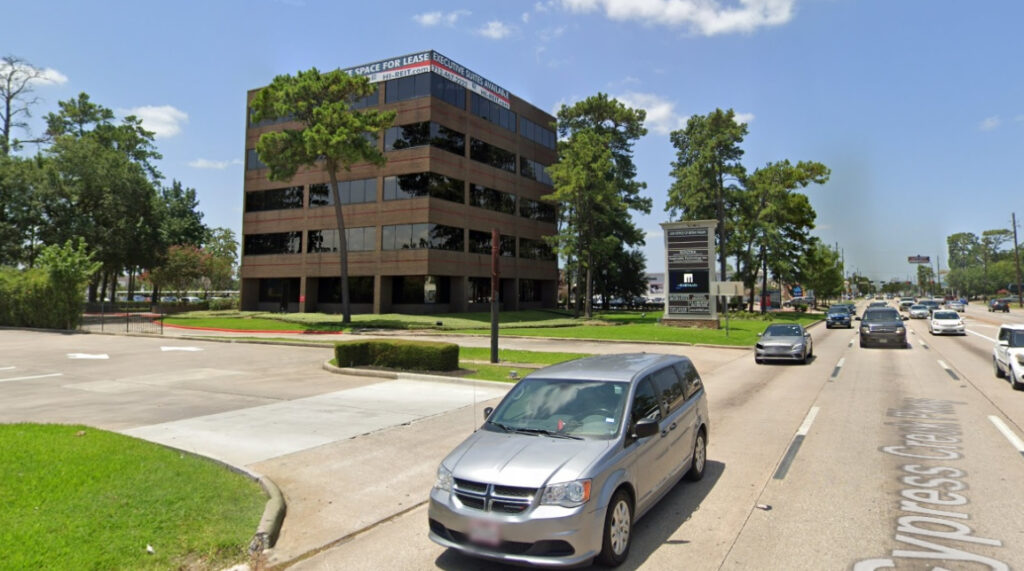 Law office building of Bryan Fagan, PLLC on Cypress Creek Parkway, featuring large windows, "Space for Lease" signage, surrounded by trees and traffic.